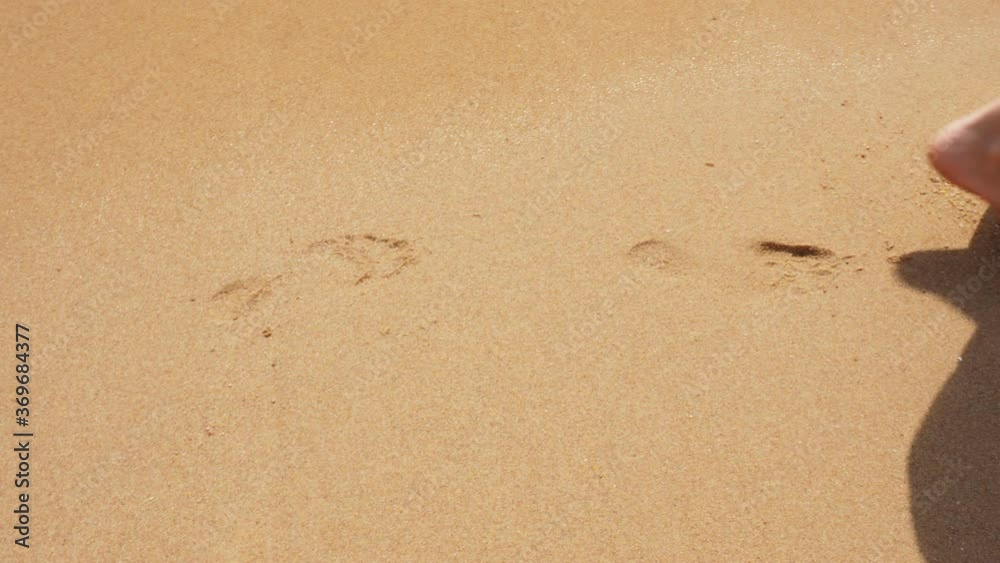 close-up, female bare feet walk along the beach, leaving footprints in sand. they are washed away by the soft sea surf. sea vacation concept close-up, female bare feet walk along the beach, leaving footprints in sand. they are washed away by the soft sea surf. sea vacation concept