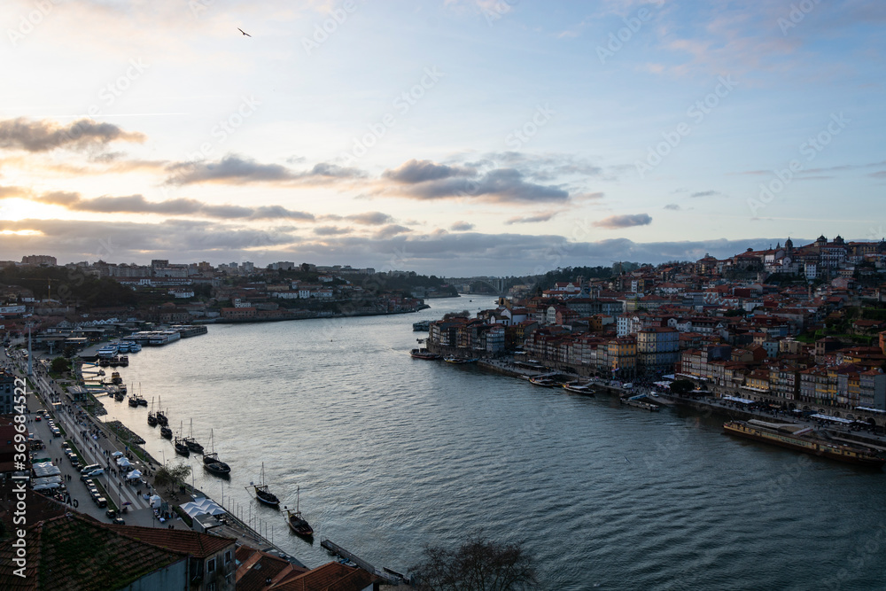 View to the city of Porto (Portugal) and Douro river from D. Luis I bridge with cloudy sky, at sunset
