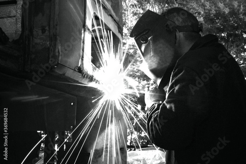 Welder welds metal on machine with sparks