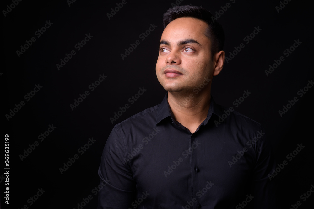 Portrait of young handsome Indian businessman against black background Portrait of young handsome Indian businessman against black background