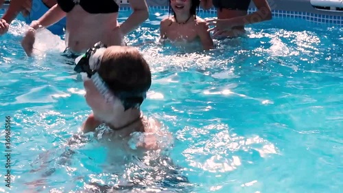 Child swimming in a swimming pool while people practicing water aerobics