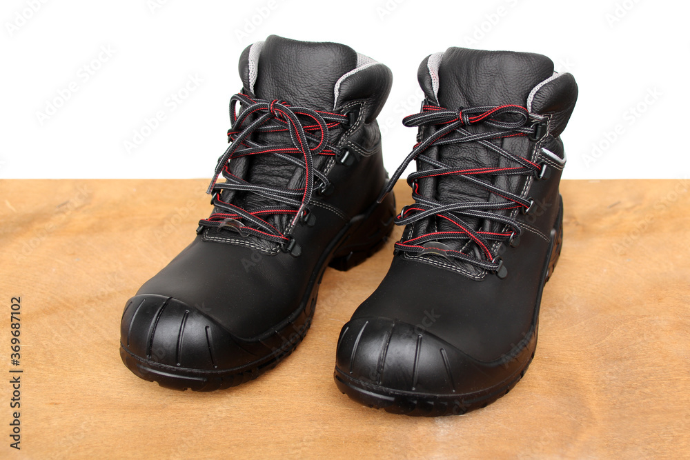 pair of new black work boots made of genuine leather with a reinforced cape, the concept of special shoes for different professions
