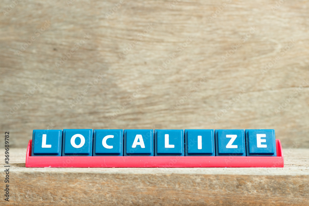 Tile letter on red rack in word localize on wood background Tile letter on red rack in word localize on wood background