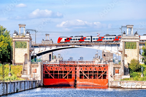 historical moscow city moskva river canal gateway with bachelis railroad bridge landmark against blue sky background. Closeup side view of modern city metro train crossing river. Urban landscape