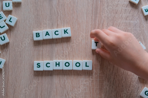 children make up from letters on a wooden table the words back to school, the concept of the beginning of the school year, homework, lessons photo