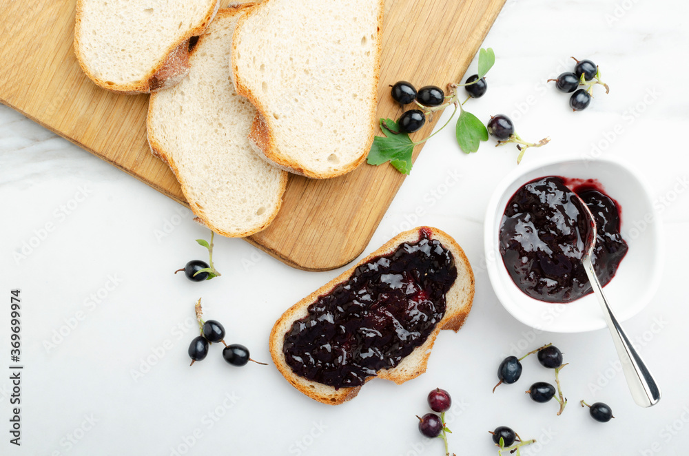Φωτογραφία Top view of wooden cutting board, slices of bread, tasty blackcurrant, bowl of s
