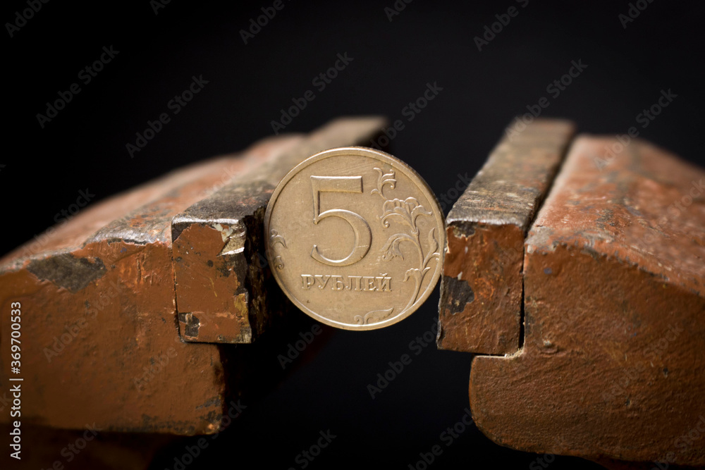 A 5-ruble coin in a metal vise. Concept of economic problems. Selective focus. Close up. A 5-ruble coin in a metal vise. Concept of economic problems. Selective focus. Close up.