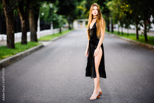 portrait of young beautiful sexy girl in black dress outdoors, attractive woman on city street