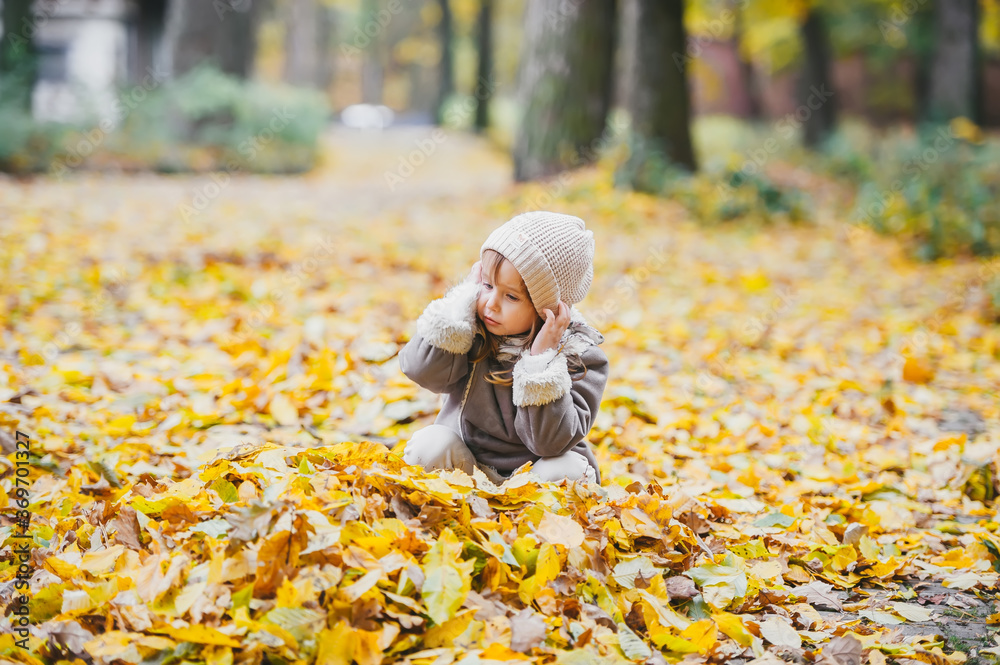 Little girl having fun in dry leaves on a beautiful autumn day. Little girl having fun in dry leaves on a beautiful autumn day.