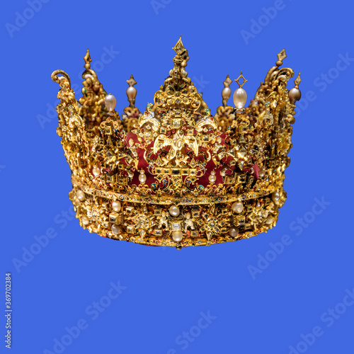 Golden crown with gems isolated on royal blue background