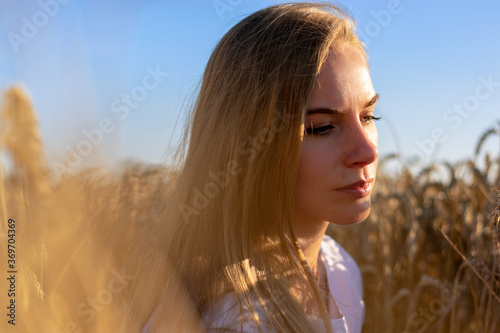 Young lady sitting at the wheat-land in a sunny day © Yelena Kovalchuk