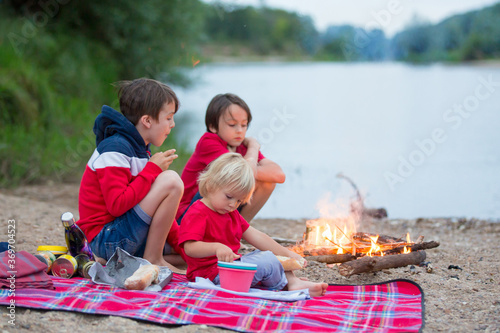 Family having picnic and campfire in the evening near river