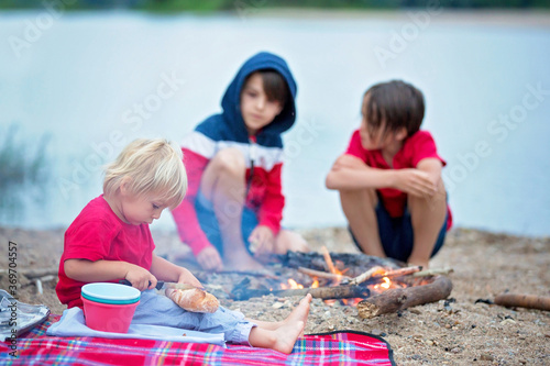 Family having picnic and campfire in the evening near river