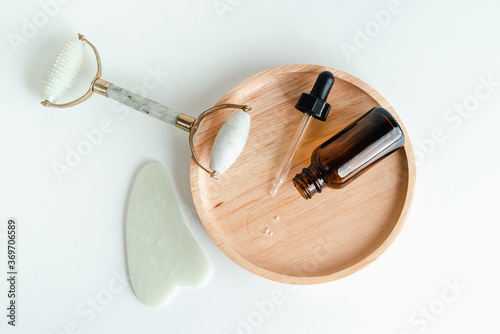 Cosmetic bottles, face serum, facial massage roller and guache scraper on background. Advertising Beauty salon, face massage. Healthy skin without wrinkles. Monochrome photo trend. Place for text photo