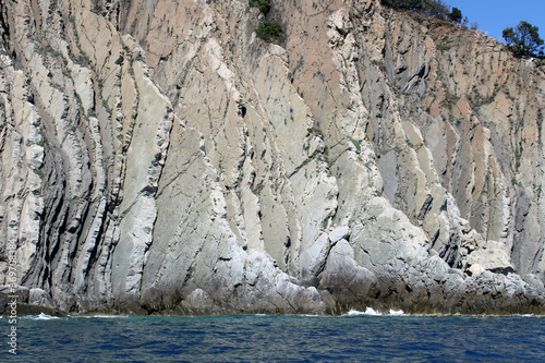 Stratificazione verticale rocciosa sulla costa con mare e frangenti photo