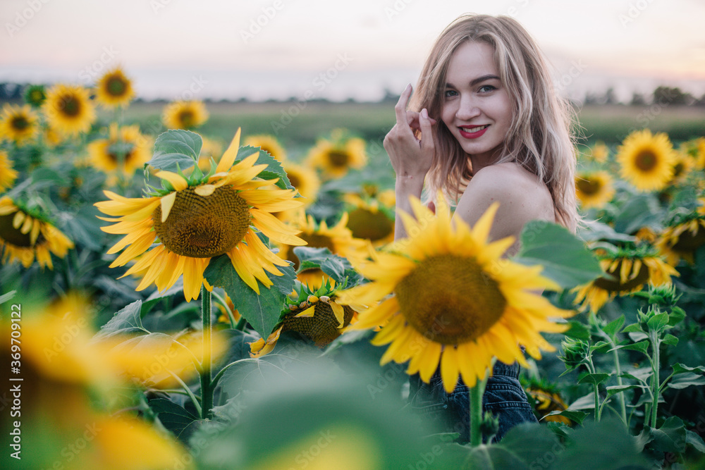 Young, slender girl topless poses at sunset in a field of sunflowers Young, slender girl topless poses at sunset in a field of sunflowers