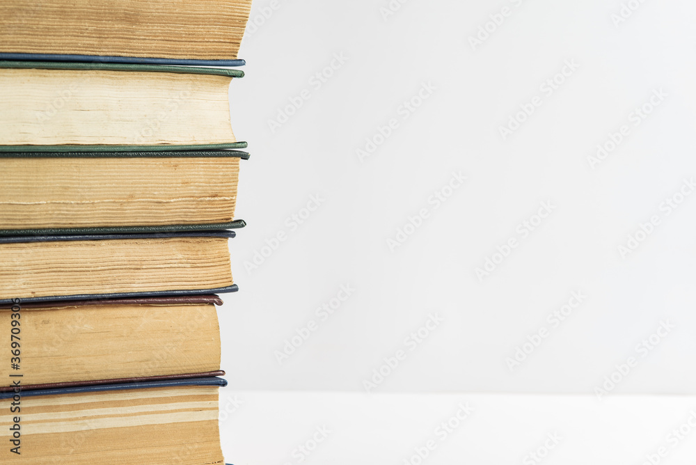 A big stack of old, faded, multicolored, yellowed books on a light background. Minimal style, copy space, side view A big stack of old, faded, multicolored, yellowed books on a light background. Minimal style, copy space, side view