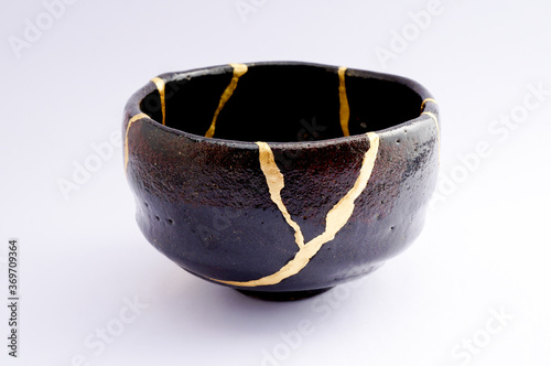 Japanese kintsugi black raku ceramic chawan, restored with real gold. Antique pottery kintsukuroi.