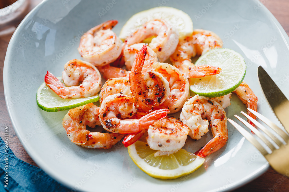 Fried tiger shrimp with lime, lemon and spices on a ceramic dish. Healthy dinner or lunch concept..