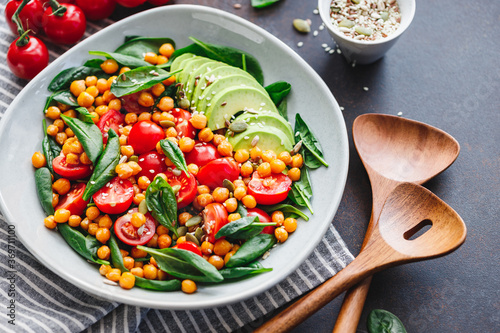 Fresh healthy salad with chickpea, avocado, cherry tomatoes and spinach.