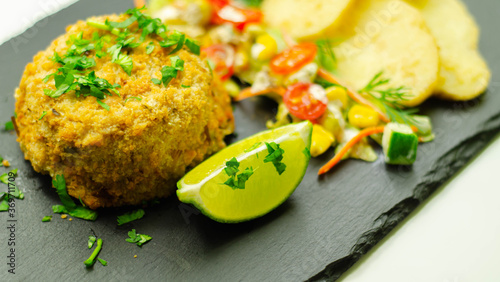 Smoked haddock fishcake with slices fried potatoes and mixed salad photo