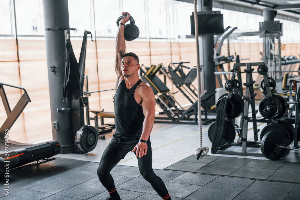 Fototapeta premium Liting weight. Young sportive strong man in black wear have workout day in gym