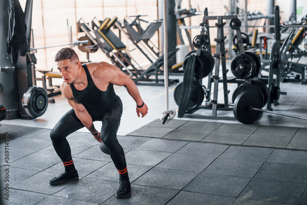 Fototapeta premium Liting weight. Young sportive strong man in black wear have workout day in gym