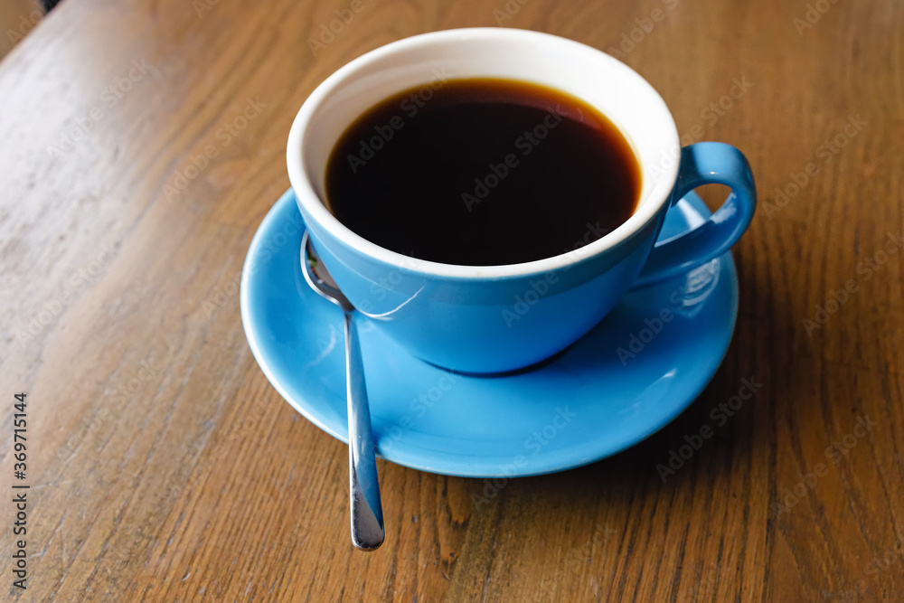 Obraz premium Blue cup with black coffee on the wooden table