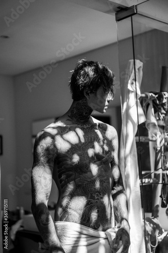handsome young man in tattoos in the bathroom after a shower in a towel.