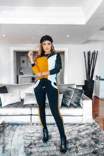 Beautiful model posing for photos in a clear room. Wearing blue pants and yellow blouse.