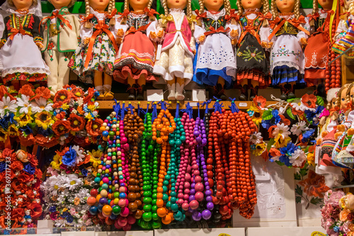 Handmade gift shop in Sukiennice Krakow, Poland. Showcase with many dolls in national costumes, multi-colored wooden beads and wreaths of bright flowers.