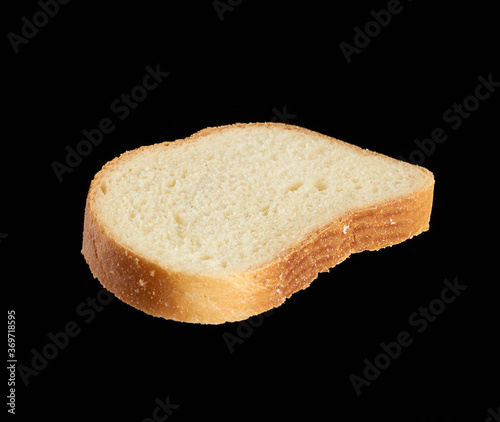 fresh oval slice of bread made from white wheat flour isolated on a black background
