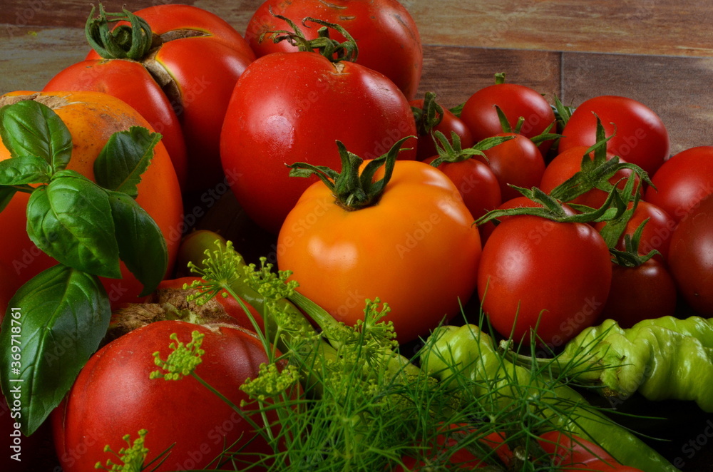 Red, ripe tomatoes and basil, dill on a dark rustic background. Harvesting organic tomatoes