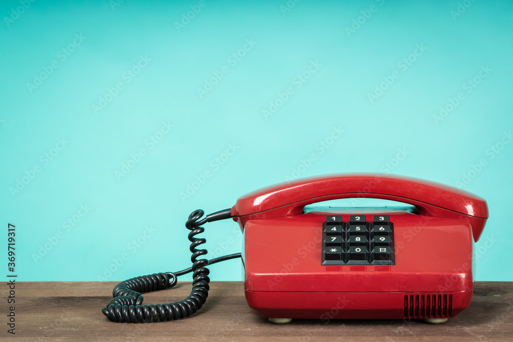 Old telephone on wooden table in front of green background. Vintage phone Old telephone on wooden table in front of green background. Vintage phone