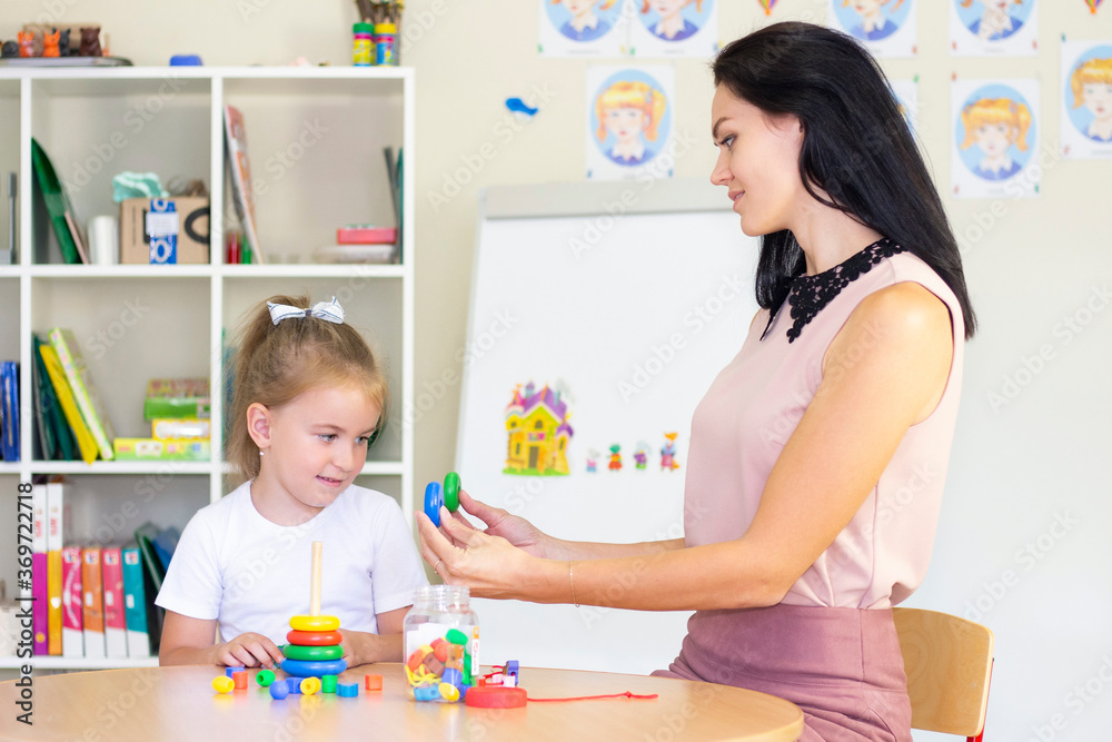 Fototapeta premium speech therapist teaches a girl. collect childrens pyramid, child development, fine motor skills