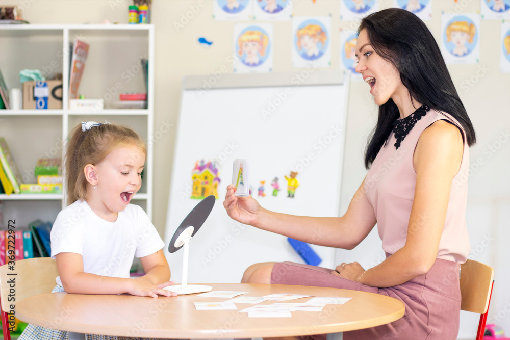 Speech therapist teaches the girl to say the letter. Mirror lesson Speech therapist teaches the girl to say the letter. Mirror lesson