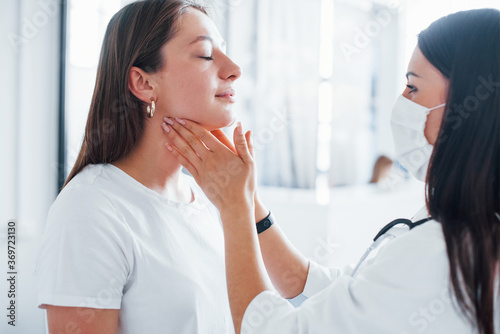 Checking lymph nodes and throat. Young woman have a visit with female doctor in modern clinic