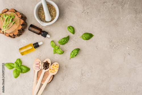 Canvas Print top view of herbs, green leaves, mortar with pestle, bottles and pills in wooden