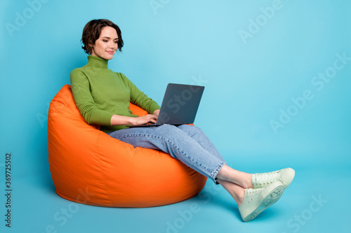 Full body profile side photo of focused ceo worker sit bean chair use laptop search information wear green casual style sweater isolated blue color background