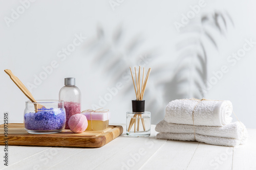 Beautiful spa composition on massage table in wellness center, copyspace. Accessories for relaxing treatments and personal care. Towels, oils, serum, sea salts and scrubs. Decorative candles.