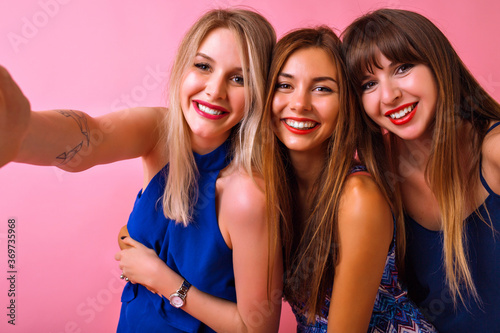 Three pretty funny woman hugs and sending and air kiss, hugs and enjoy time together, friendship goals, wearing color matching navy elegant outfit, soft toned colors.