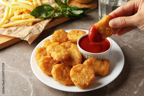Female hand hold nuggets over the table with nuggets and fried potato photo