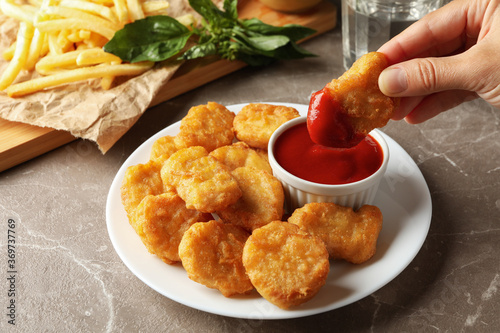 Photos Female hand hold nuggets over the table with nuggets and fried potato