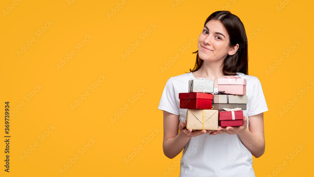 Holiday sale. Special offer. Cheerful woman in white t-shirt holding gift boxes pile isolated on orange copy space. Happy birthday. Festive occasion. Greeting congratulation. Holiday sale. Special offer. Cheerful woman in white t-shirt holding gift boxes pile isolated on orange copy space. Happy birthday. Festive occasion. Greeting congratulation.
