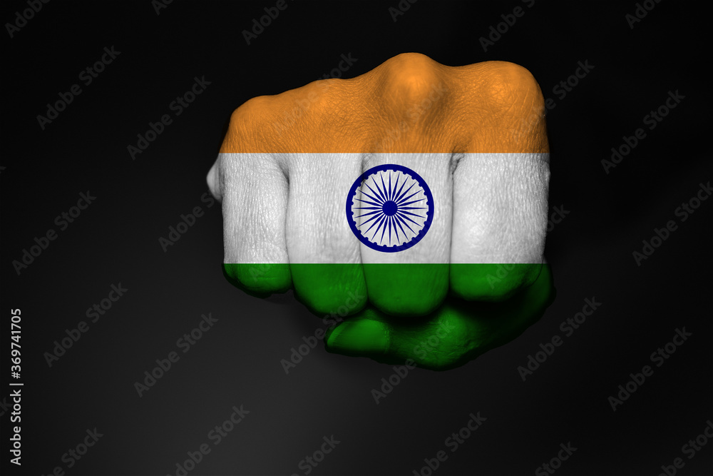 Low key picture of a fist painted in colors of Indian flag on a black background