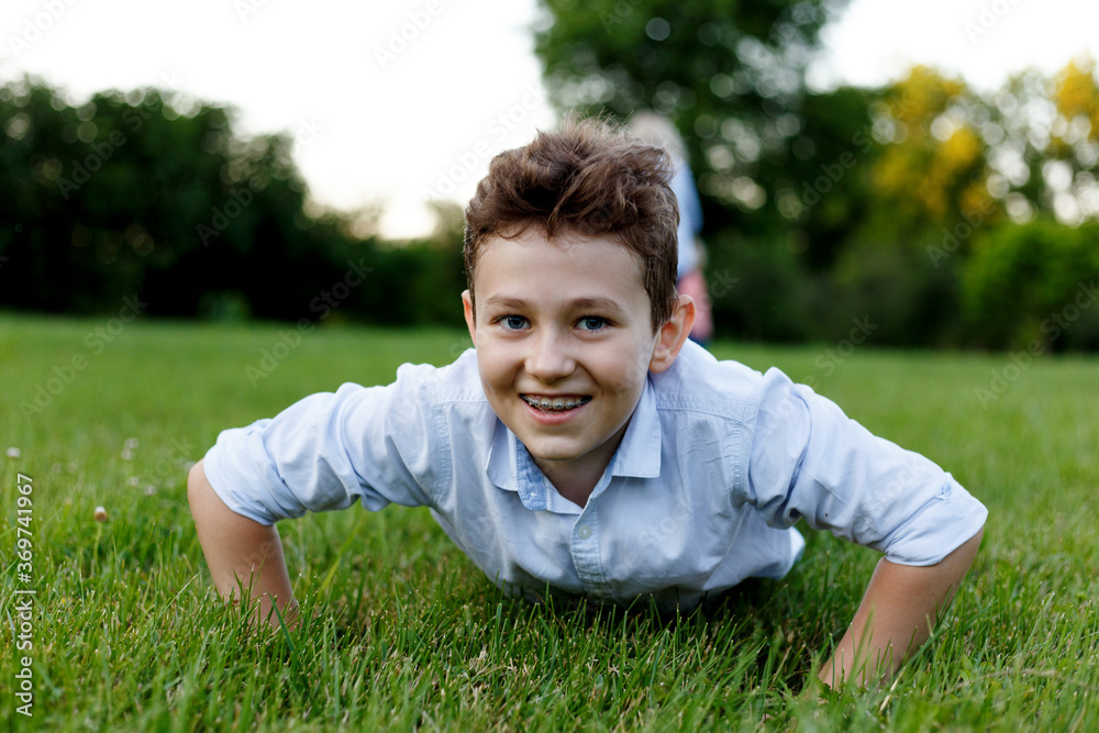 Young man doing push-ups in the park. Schoolboy go in for sports.