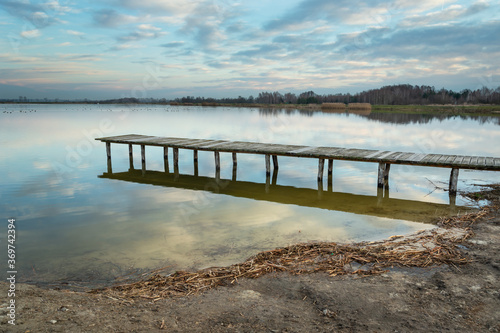 Long wooden bridge on a lake and evening clouds photo