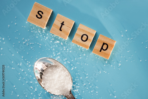 Word STOP made of wooden letters and rafinated sugar on blue background. photo