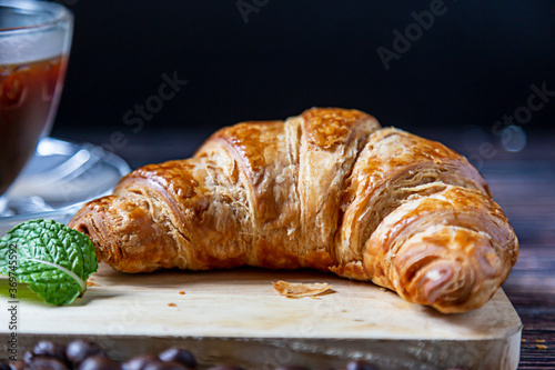 Croissant with mint leaves to decorate on the wood.