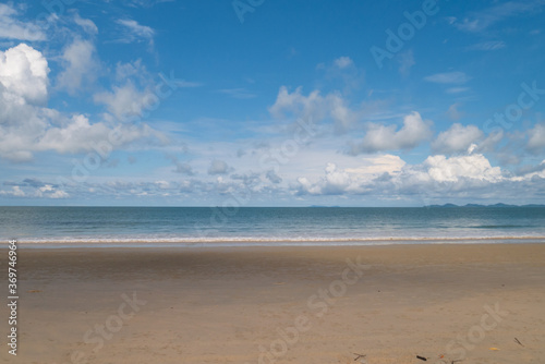 Nature background of seashore beach wave and coastline, clear blue sky with cloud, and sunlight water surface for holiday relaxation lifestyle landscape concept